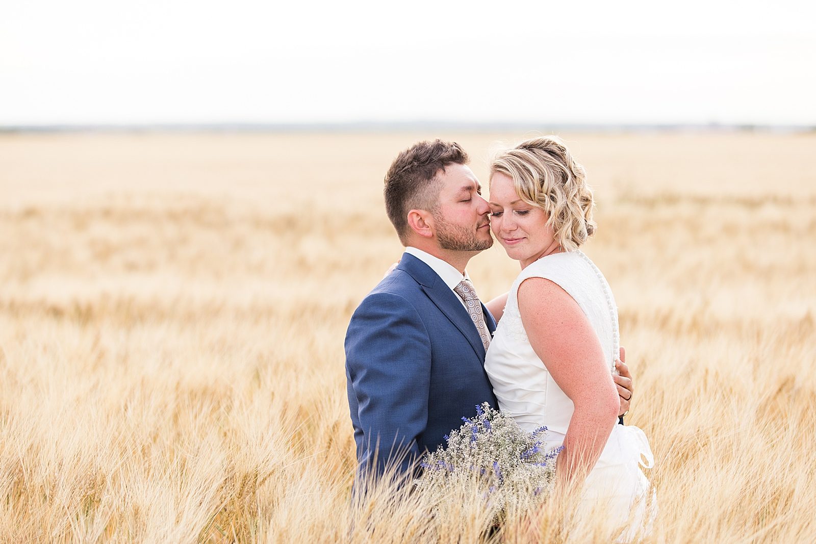 Bride and groom standing in a wheat field