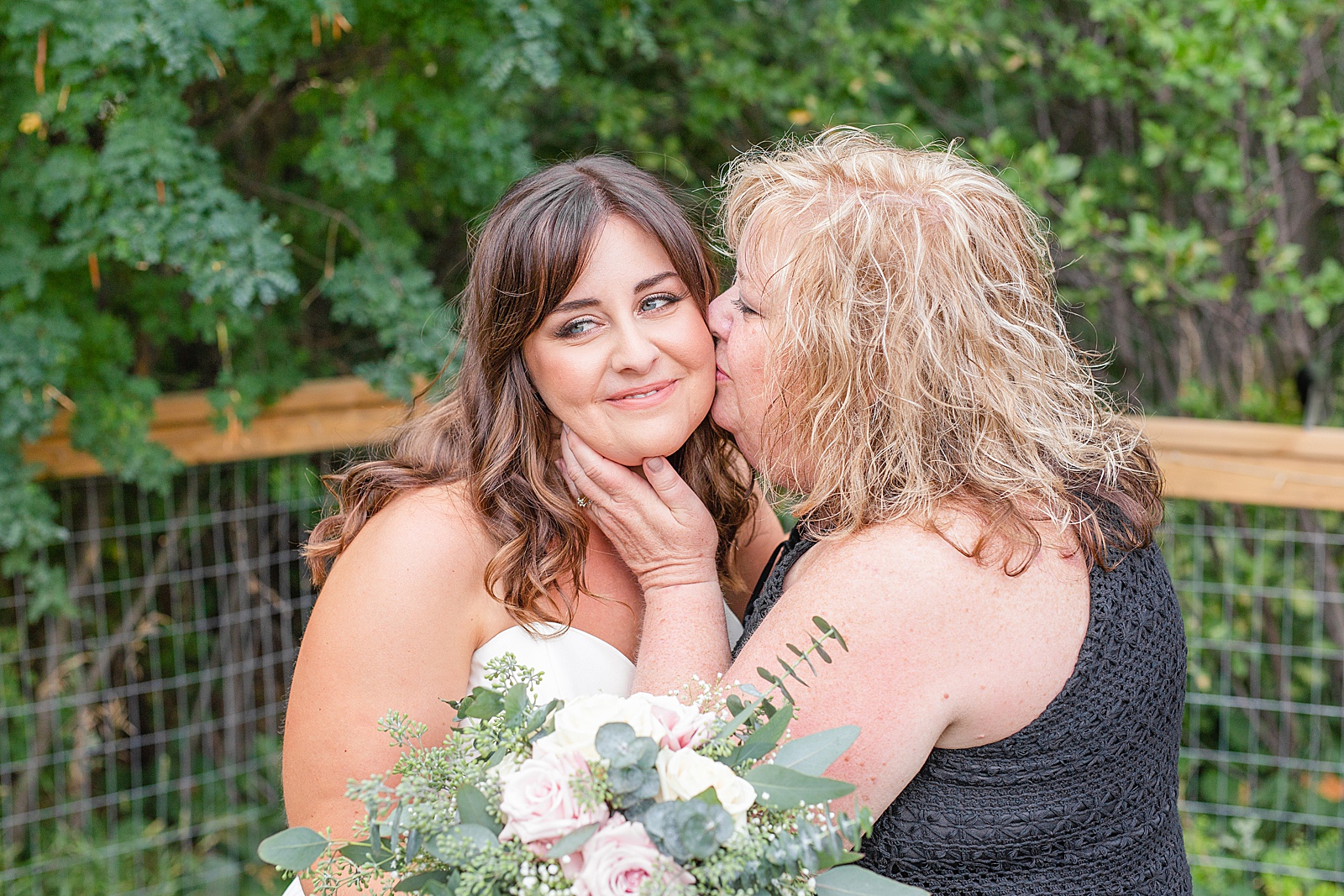 mom kissing daughter bride on the cheek