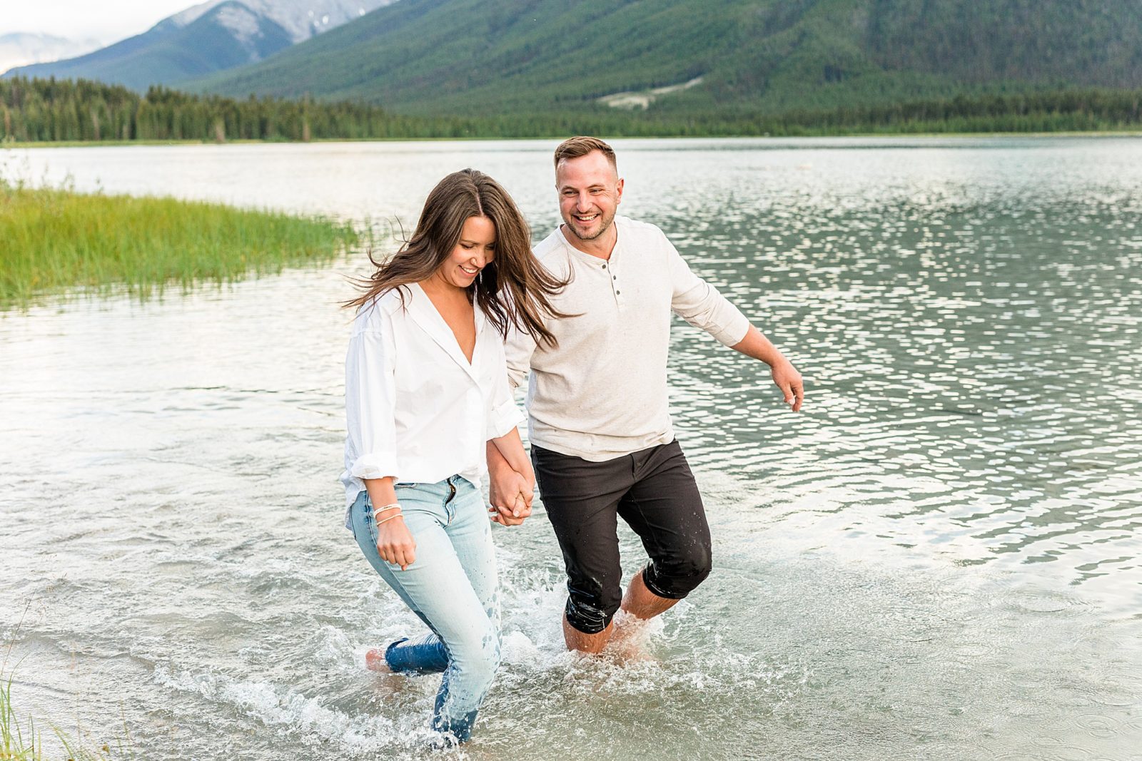 Couple standing in front of mountains  in a lake in Kananaskis 